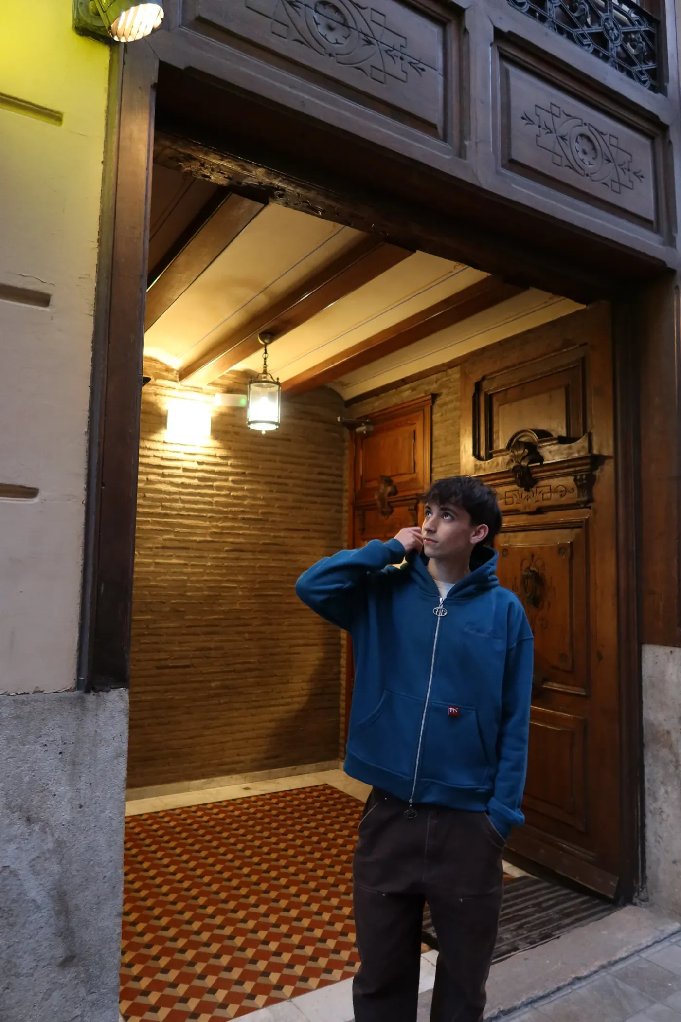 Blue Hoodie Zip frente a un portal de madera