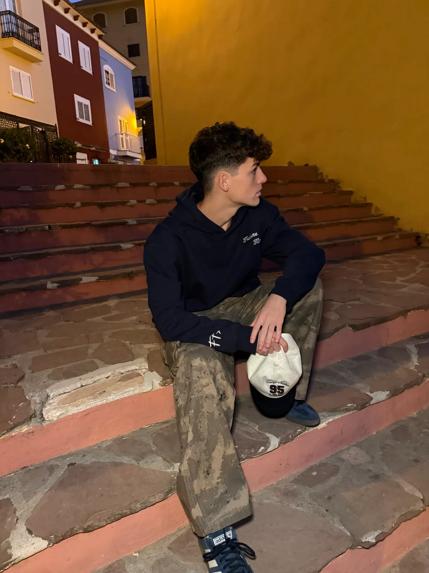 Navy Blue Hoodie sentado en una escalera de noche